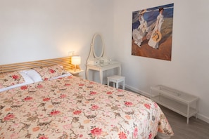 Une chambre à coucher avec un lit, une table de chevet avec une lampe, une commode, un miroir et un tableau accroché au mur.