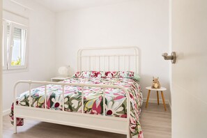 Ein Schlafzimmer mit einem Bett, einem Nachttisch und einem kleinen runden Tisch mit einem Stofftier.