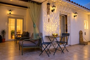 Eine Terrasse mit Tisch und Stühlen, einer Zierleuchte und einer Wandlampe.