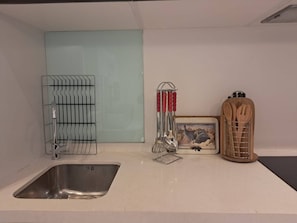 A kitchen with a stainless steel sink, a glass backsplash, and a wooden utensil holder. - Stylish Sandton Apartment With Stunning City Views (Johannesburg)