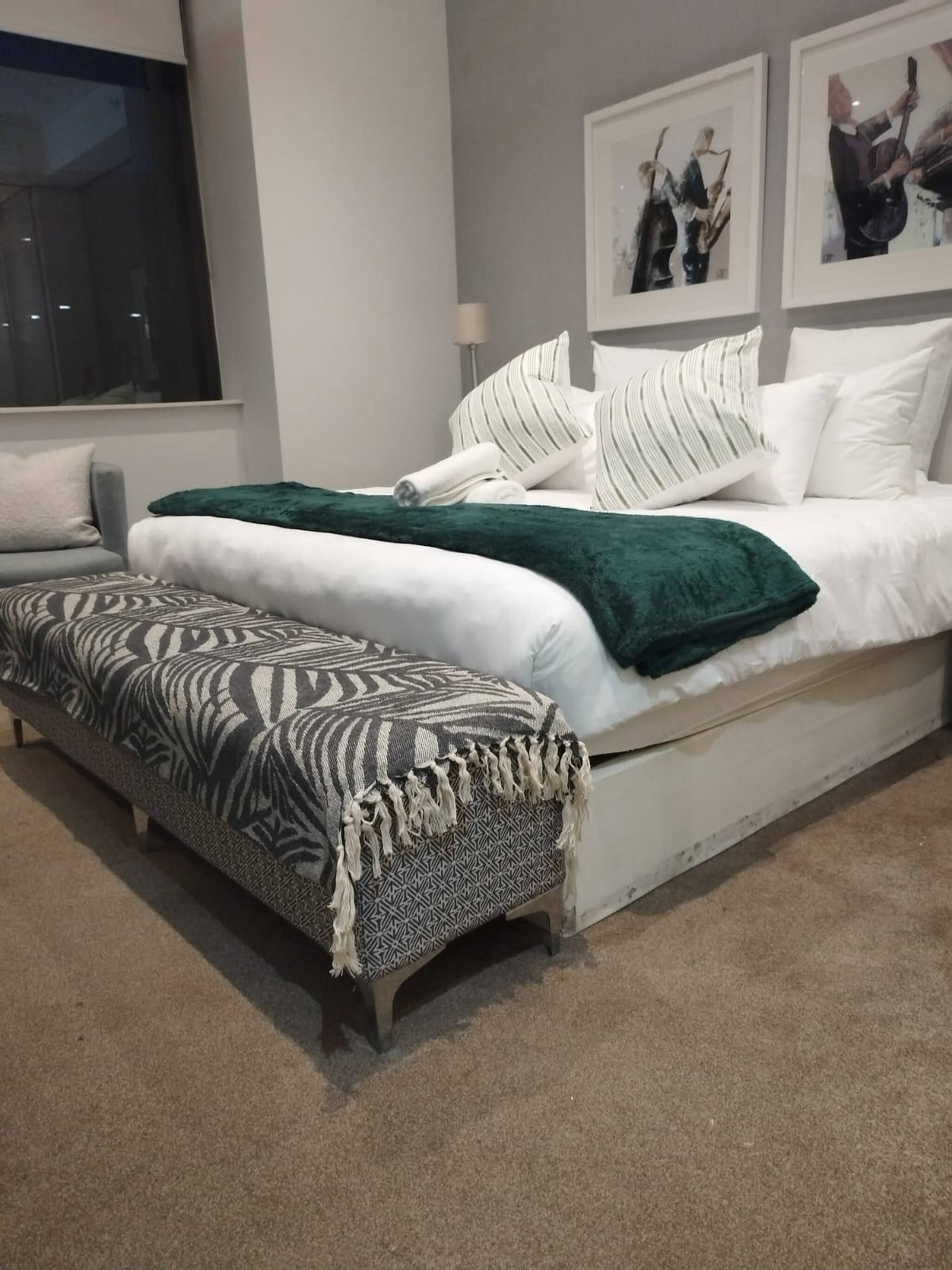 Un dormitorio moderno con una cama grande, una mesita de noche, una lámpara y una ventana.