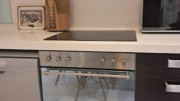 Una cocina con horno empotrado, microondas y un portalápices de madera.