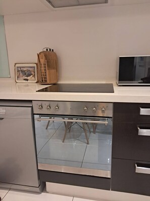 A kitchen with a built-in oven, a microwave, and a wooden utensil holder. - Stylish Sandton Apartment With Stunning City Views (Johannesburg)