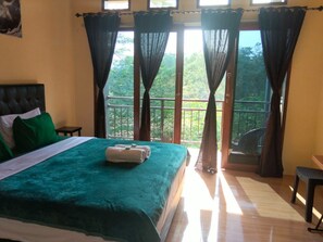 A bedroom with a bed, a nightstand, a window with curtains, and a balcony with a railing. - The Sanduk Inn (Rinding Batu)