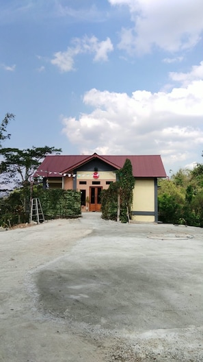 A building with a red roof and a beige facade, surrounded by greenery.