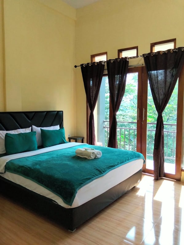 A hotel room with a bed, curtains, and a view of greenery.