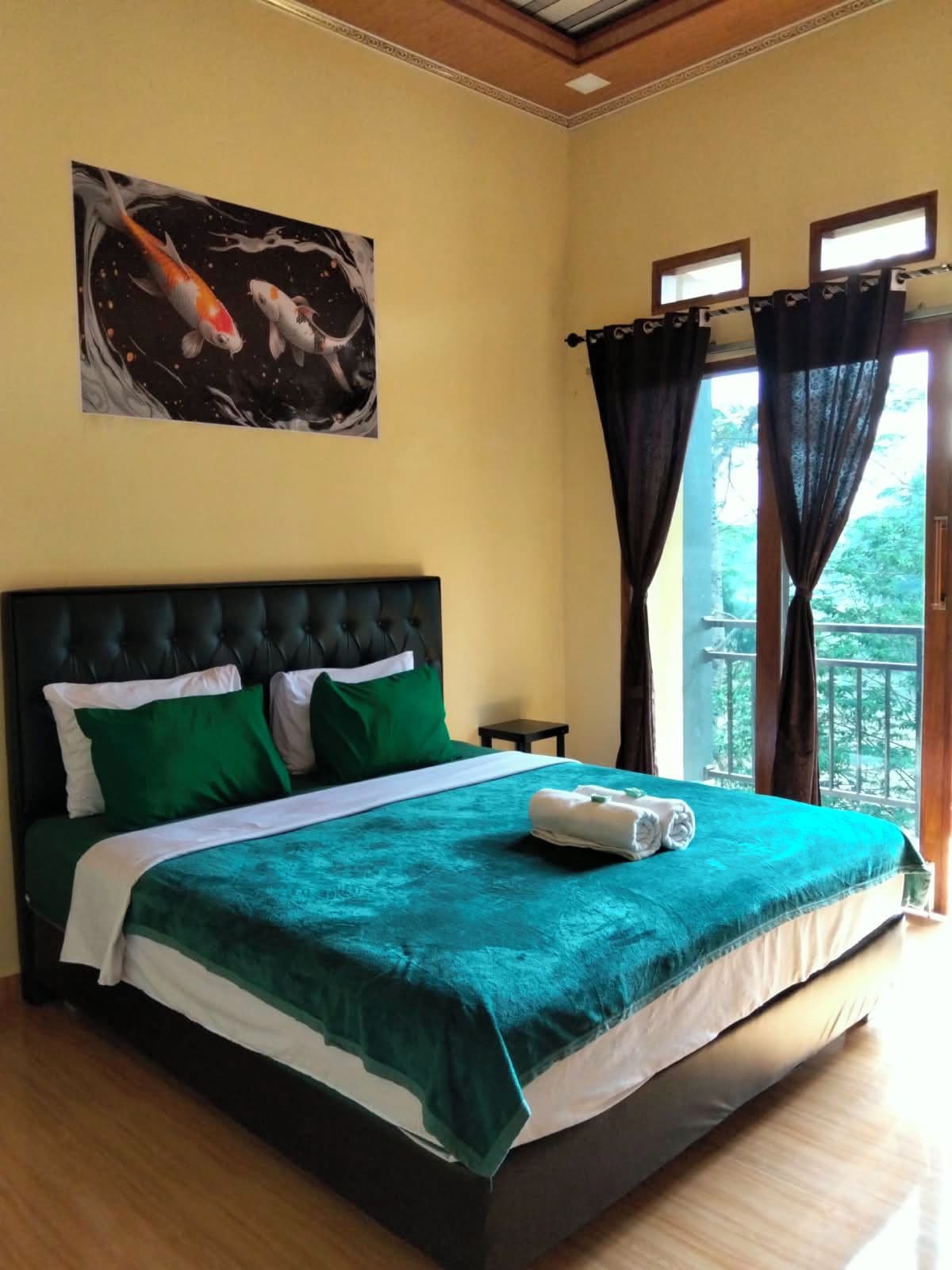 A hotel room with a bed, a nightstand, a painting of fish, and a balcony with curtains.