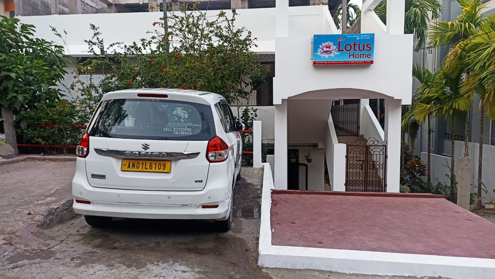 A white car parked in front of a building with a sign that reads 'The Lotus Home.'