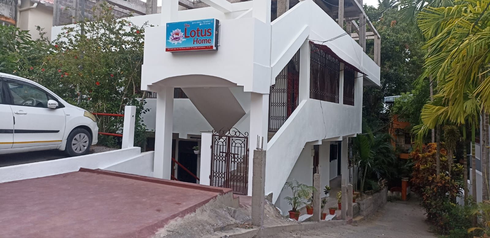A white two-story building with a sign reading 'The Lotus Home.'