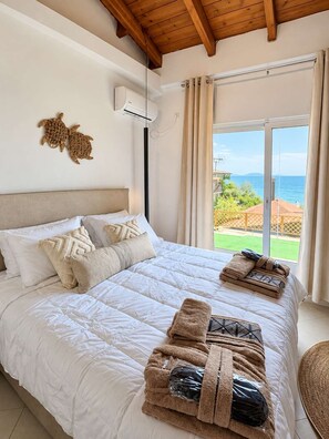 Ein Schlafzimmer mit einem großen Bett, einem Deckenventilator, Meerblick und einem Balkon.