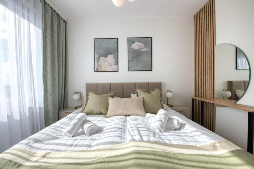 A modern bedroom with a bed, two bedside tables, a mirror, and artwork on the wall.
