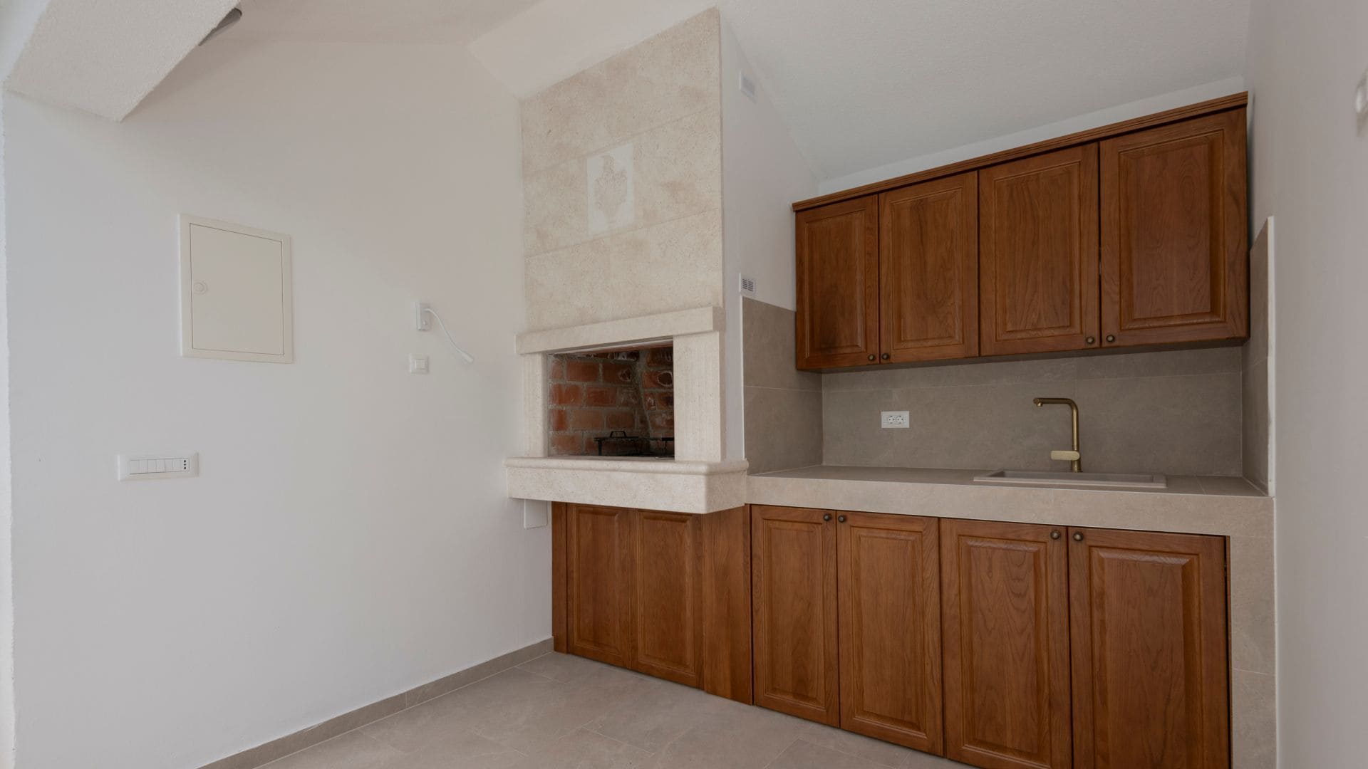 A kitchen with wooden cabinets, a built-in brick oven, and a countertop.
