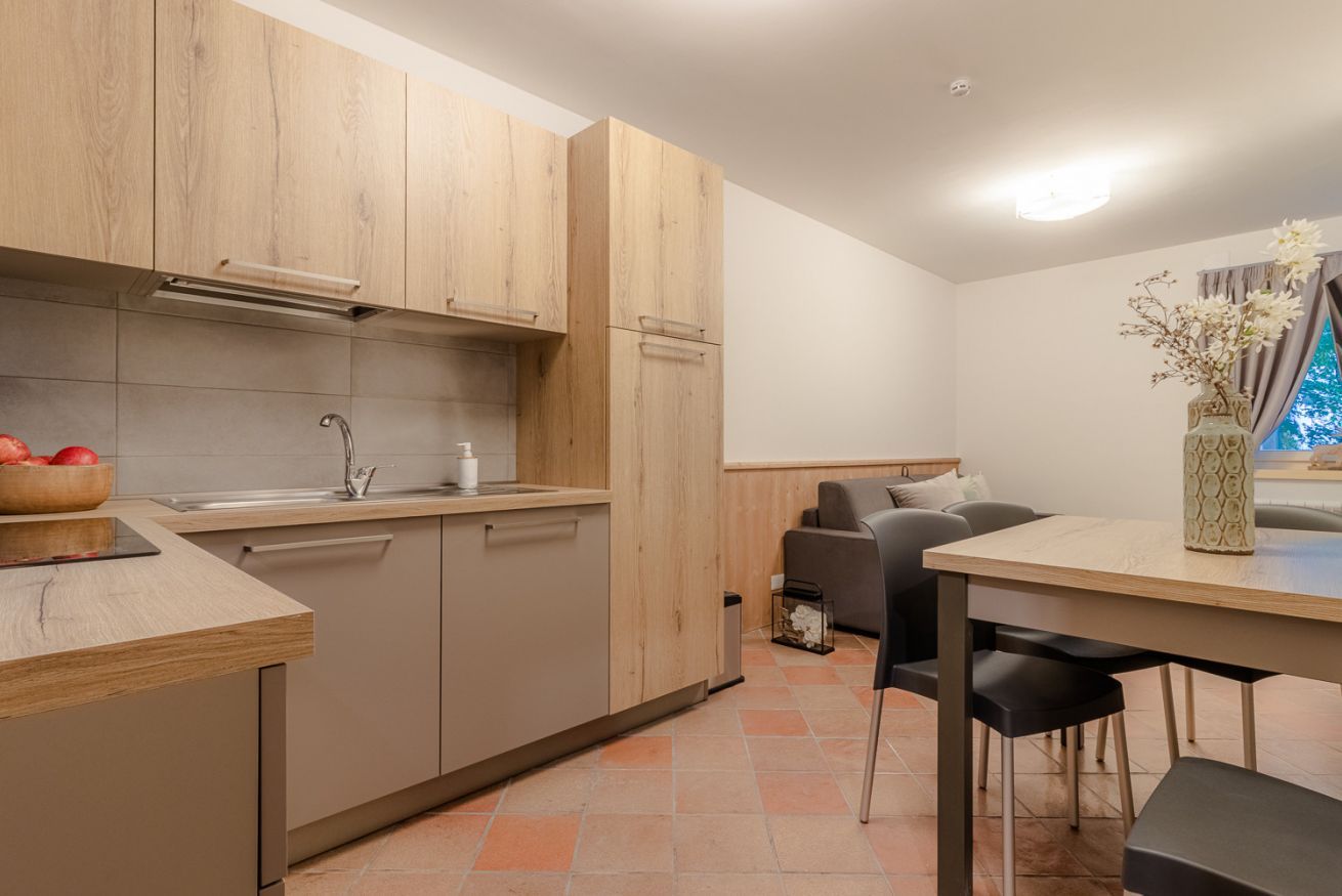 Une cuisine moderne avec des meubles en bois, un four encastré et un coin repas comprenant une table et des chaises.