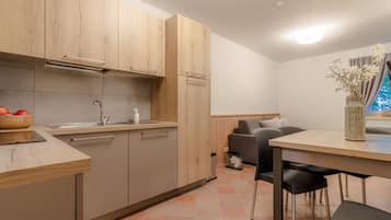 A modern kitchen with wooden cabinets, a built-in oven, and a dining area with a table and chairs.