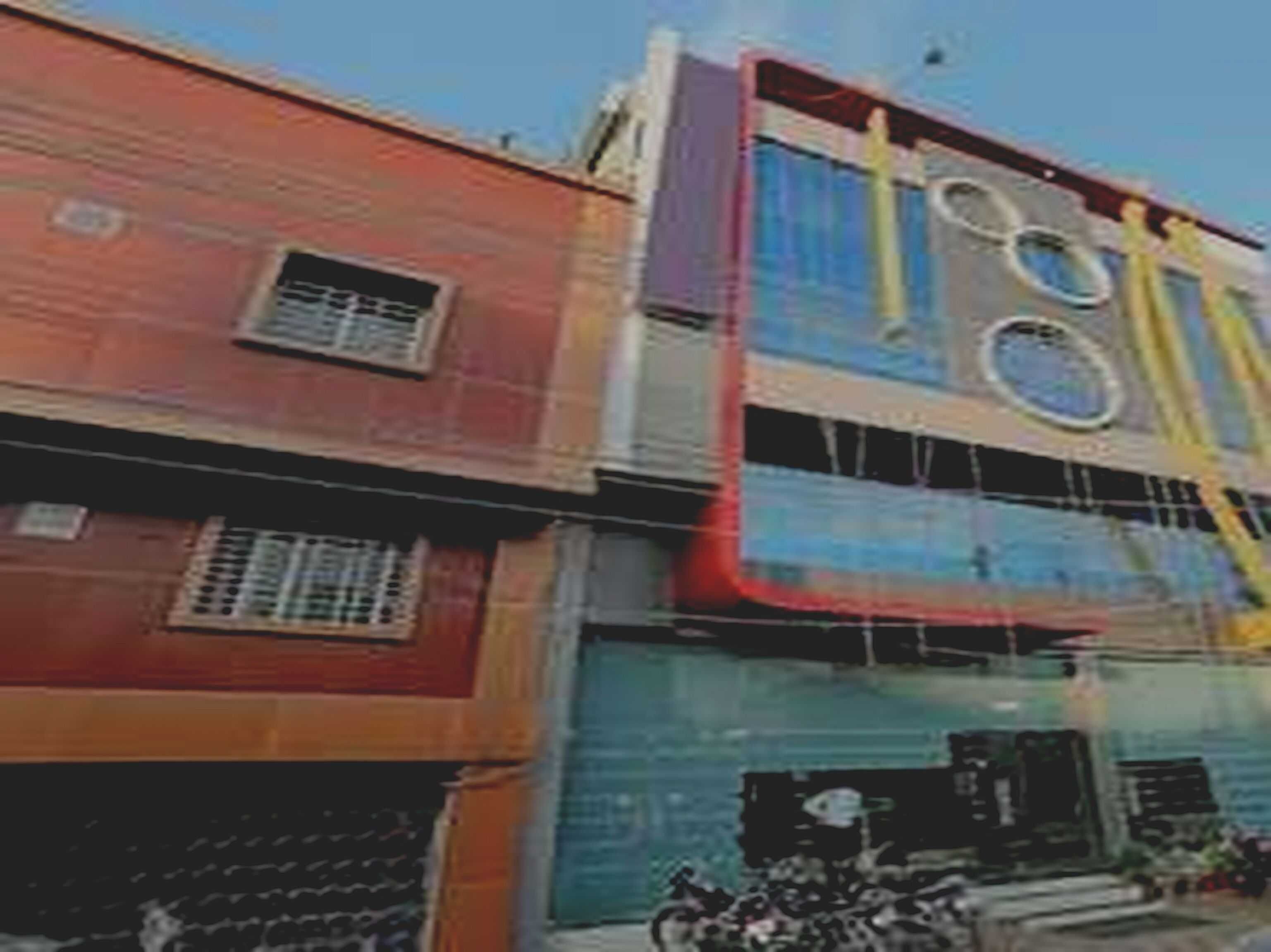 A multi-story building with a red facade and a blue upper section.