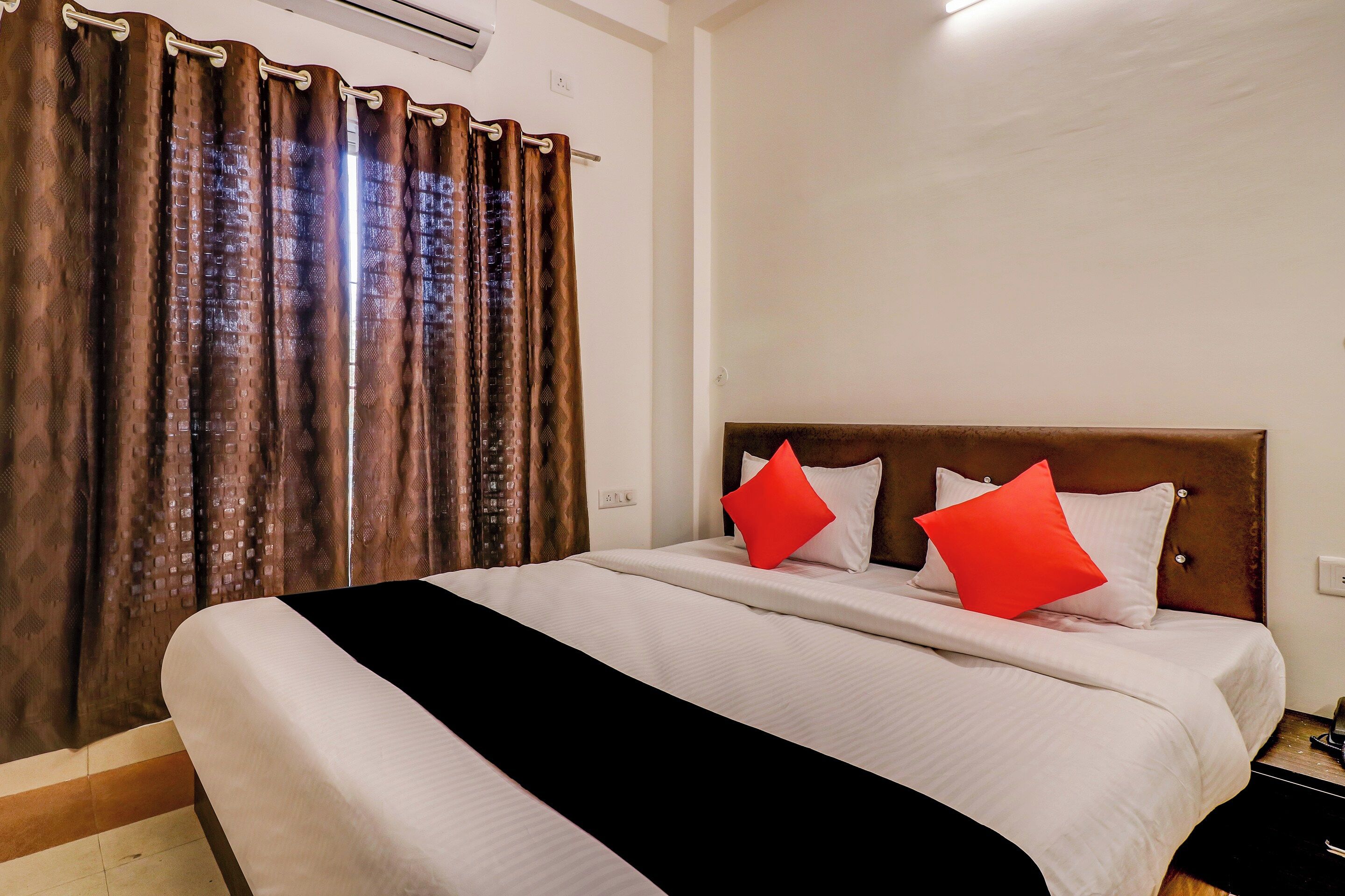 Ein Hotelzimmer mit Bett, Vorhängen und Kopfteil.