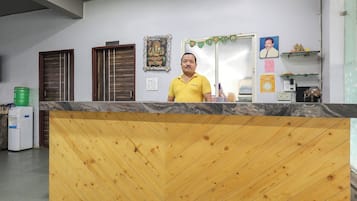 Ein Empfangsschalter mit Holzausstattung, eine Küchenzeile mit zwei Türen und eine Wand mit religiösen Verzierungen.