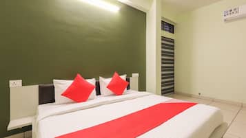 Ein Hotelzimmer mit einem Bett, einem Nachttisch, einer Wand-Klimaanlage und einem Fenster mit Jalousien.