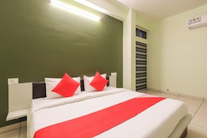 Una habitación de hotel con cama, mesita de noche, aire acondicionado montado en la pared y ventana con persianas.