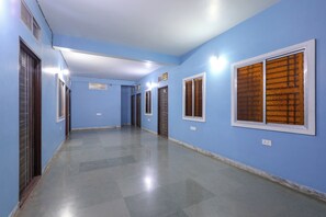 Un pasillo con paredes azules, varias puertas y piso de baldosas.