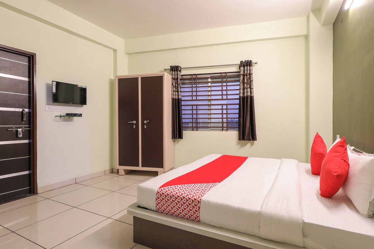 A hotel room with a bed, a wardrobe, a television, and a window with curtains.