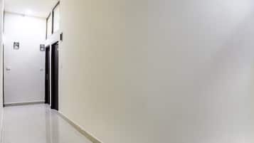 Un pasillo con puertas a la izquierda, que conduce a una habitación con ventana.