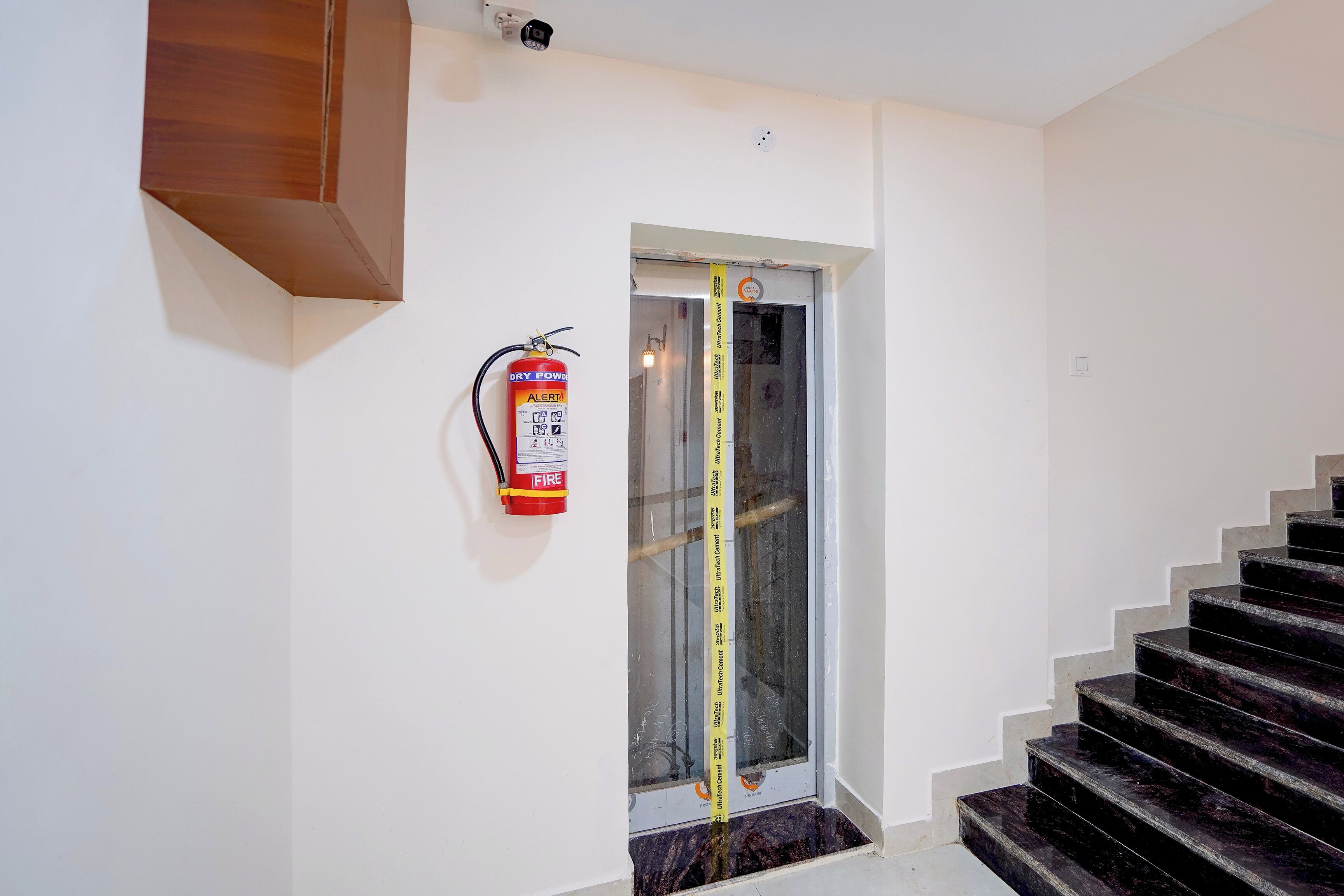Eine Treppe mit einem an der Wand befestigten Feuerlöscher und einem Zollstock am Türrahmen.