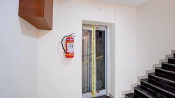 Eine Treppe mit einem an der Wand befestigten Feuerlöscher und einem Zollstock am Türrahmen.