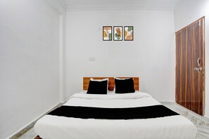 Ein Schlafzimmer mit einem Bett, einem Holzschrank und drei gerahmten Kunstwerken an der Wand.