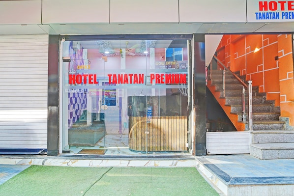 Entrada de un hotel con puerta de vidrio, una escalera visible a la derecha y un cartel que indica 'HOTEL TANATAN PREMIUM'.