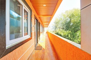 Un pasillo con ventanas en un lado y vistas al exterior con vegetación.
