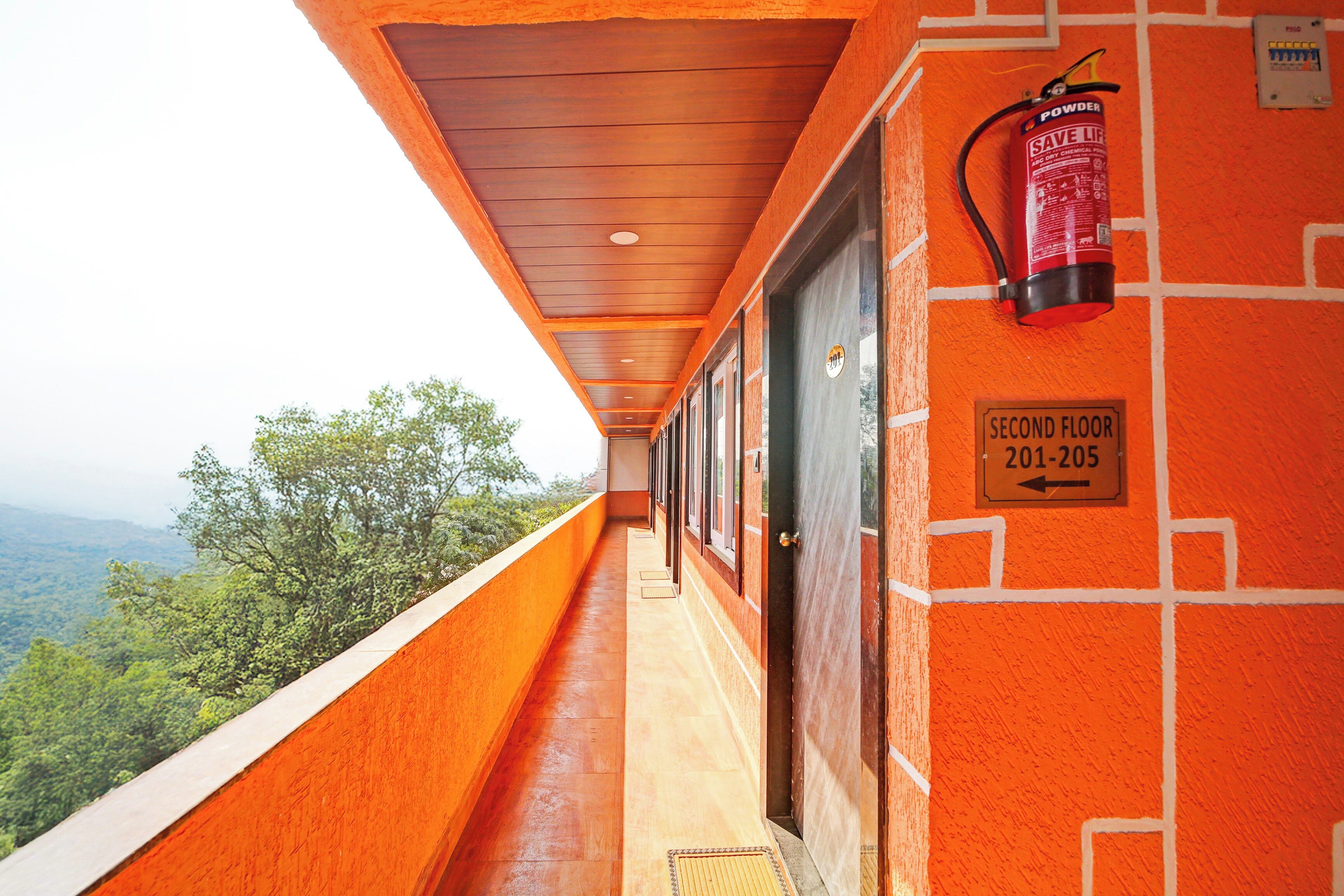 A corridor with a fire extinguisher mounted on the wall, a sign indicating the second floor, and a view of the outdoors.