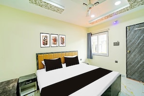 Una habitación de hotel con una cama, una mesita de noche, un ventanal con cortinas y un ventilador de techo.