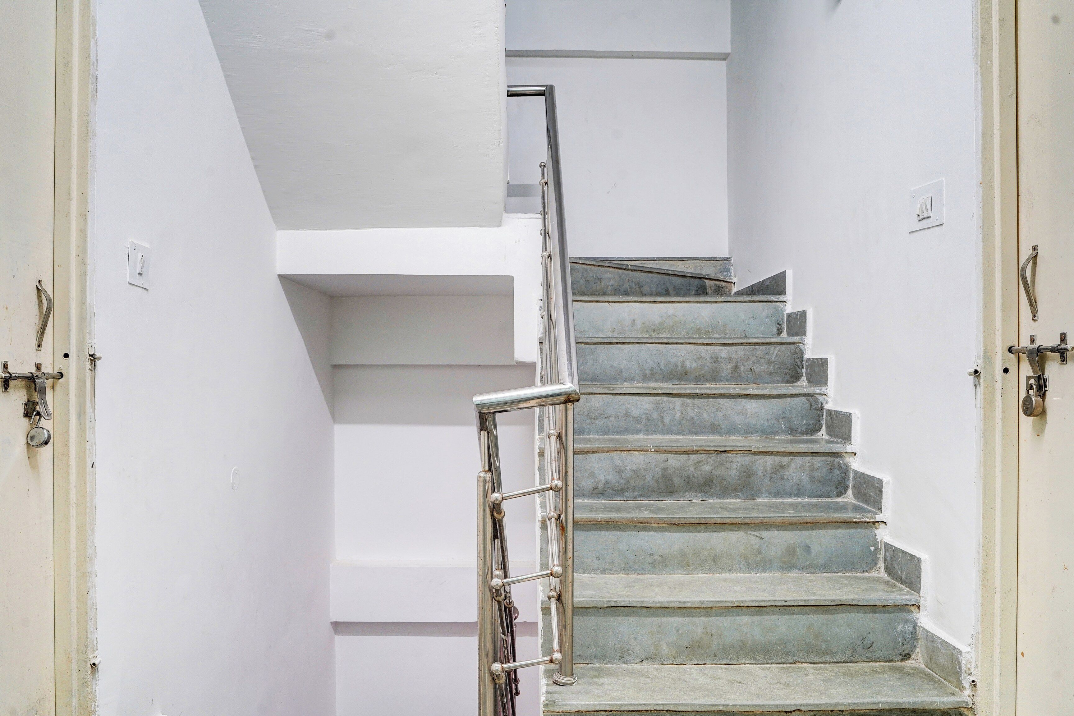 Eine Treppe mit Metallhandläufen und einer weißen Wand.