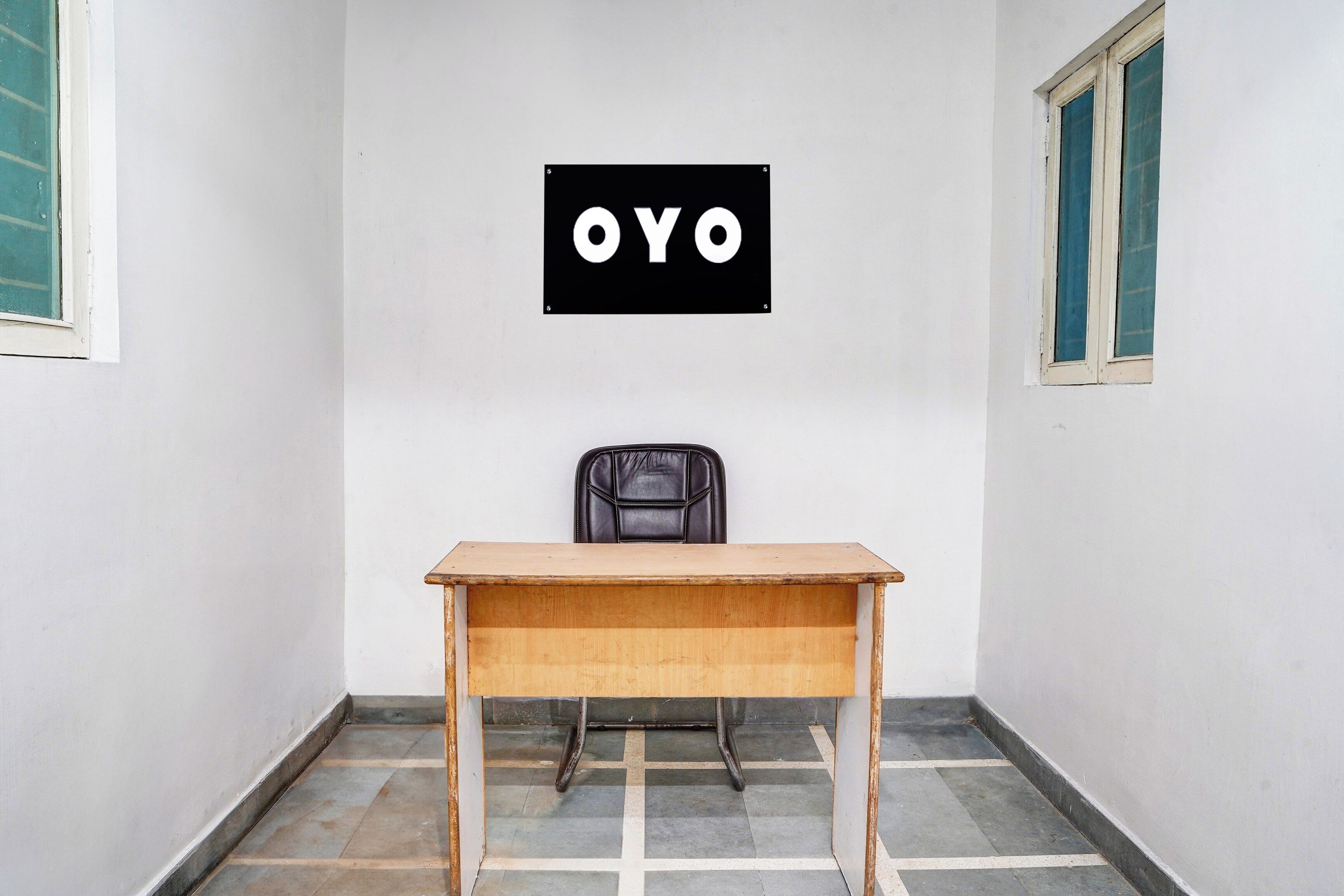 Ein Zimmer mit einem Holztisch, einem schwarzen Stuhl und einem an der Wand befestigten Schild mit den Buchstaben 'OYO'.
