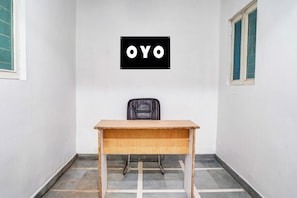 Une pièce avec un bureau en bois, une chaise noire et une enseigne fixée au mur avec les lettres « OYO ».