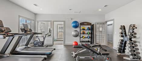A gym with treadmills, a stationary bike, a bench press, and a rack of dumbbells.
