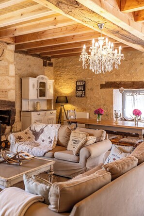 Una sala de estar acogedora con chimenea, un candelabro y una pared de piedra.