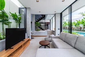 Un salon moderne doté d’un téléviseur à écran plat, d’un canapé, d’une table basse et d’un escalier menant à un niveau supérieur.
