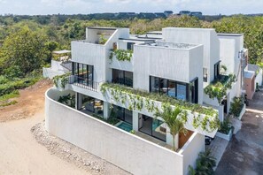 A modern building with multiple levels, large windows, and a rooftop garden. - Ave Fenix 2BR Villas Balangan (Jimbaran)