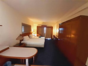 A hotel room with a bed, a desk, a chair, a wardrobe, and a television. - Rainbow Paradise Homestay by Landmark (Tanjung Bungah)