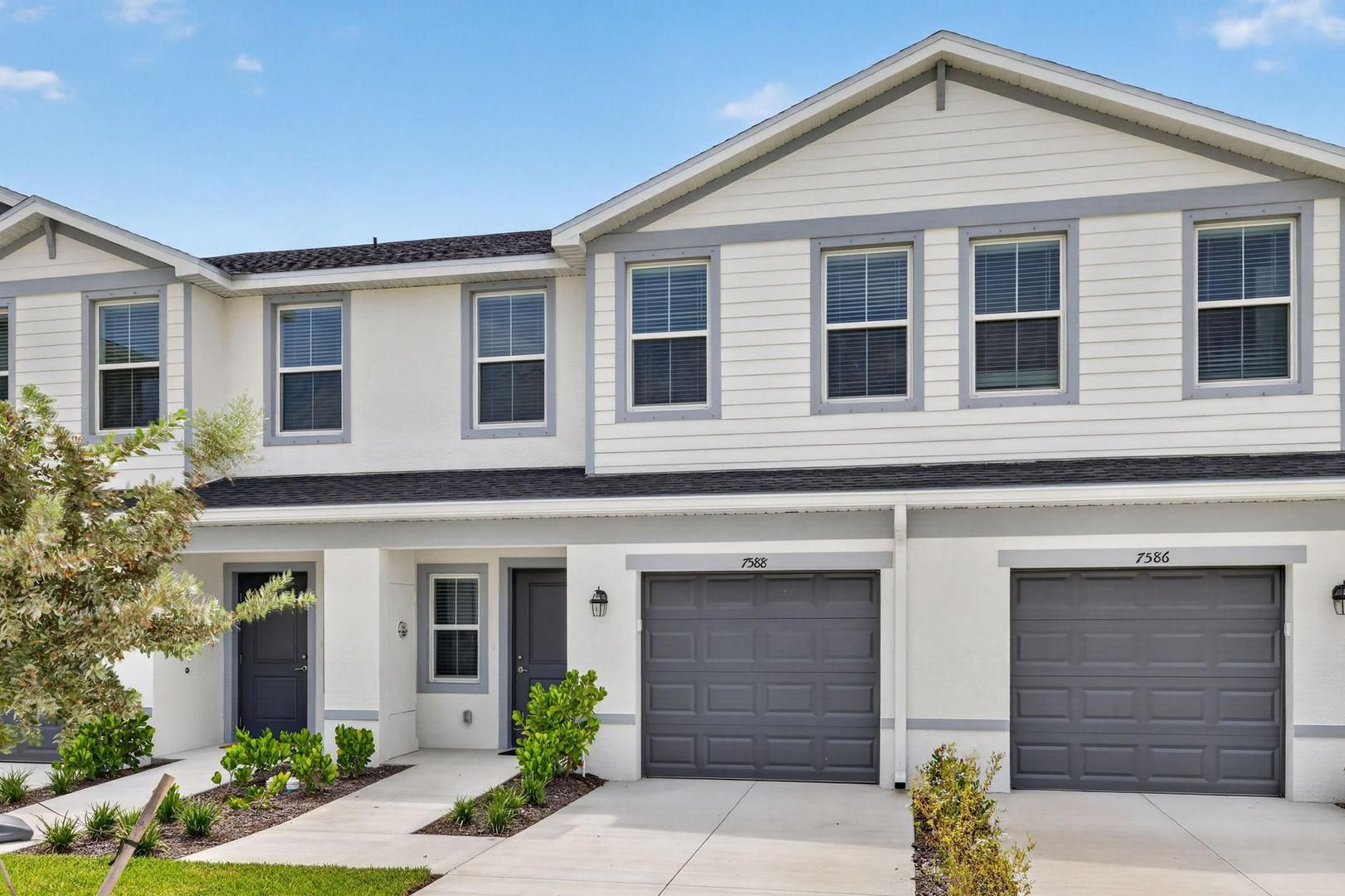 A two-story residential building with a symmetrical facade, two garage doors, and a front entrance with a door and a small porch area.