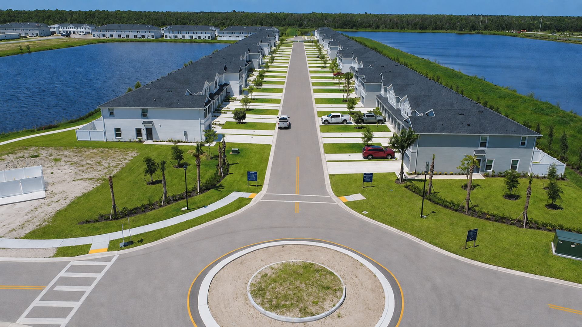 Un quartier résidentiel avec une rue principale, des maisons de chaque côté et un plan d’eau.