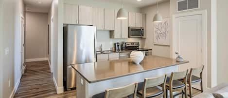 Una cocina moderna con una isla central, electrodomésticos de acero inoxidable y sillas de madera.