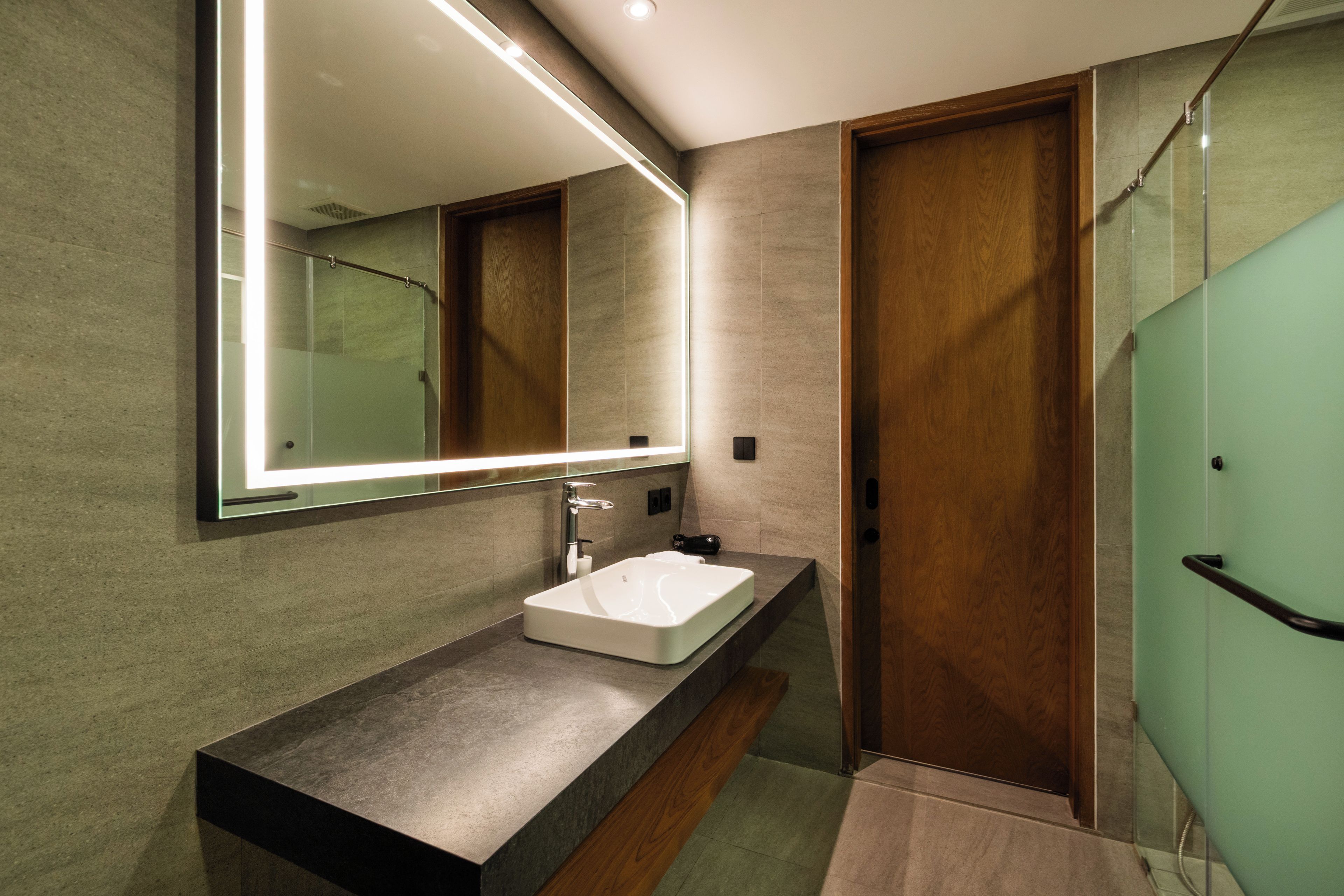 Un baño moderno con un espejo grande, un lavabo rectangular y una zona de ducha.