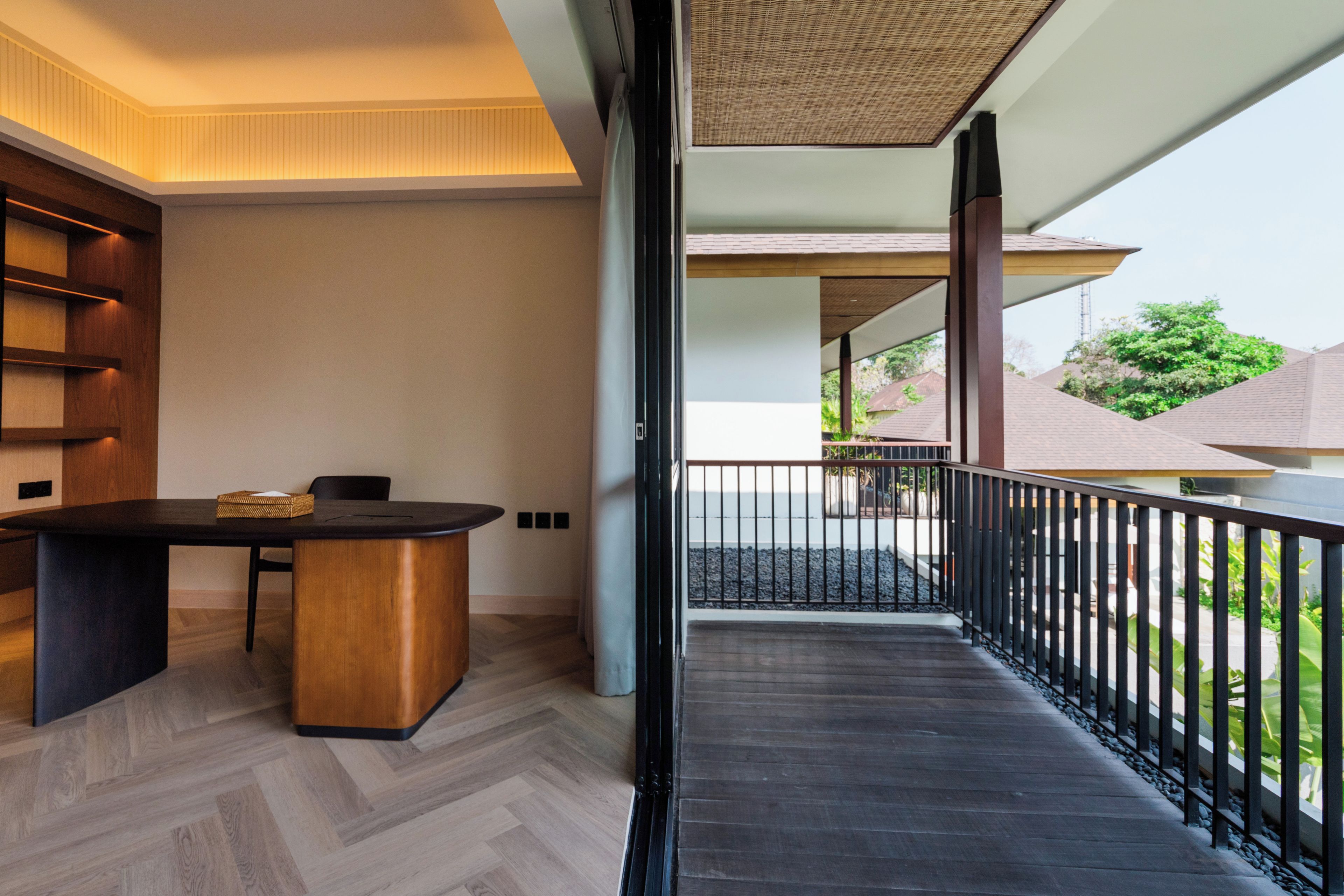 Um interior moderno com uma mesa e cadeiras de madeira, varanda com guarda-corpo e vista para o exterior.