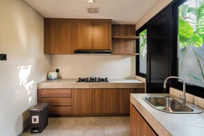 Una cocina compacta con armarios de madera, una estufa a gas y un lavaplatos de acero inoxidable.