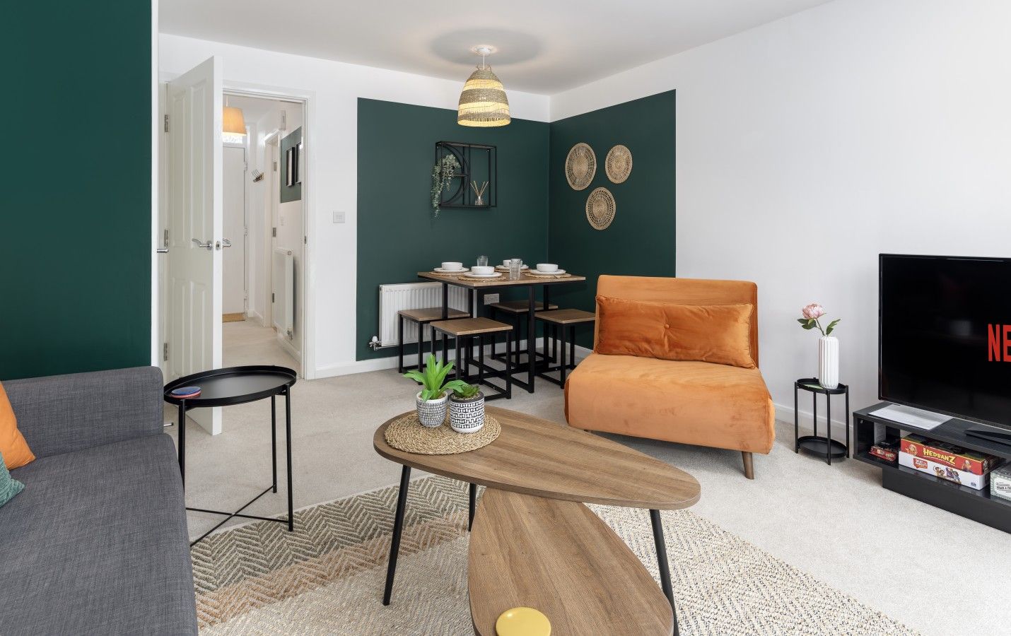 A living room with a sofa, a coffee table, a TV, and a dining area with a table and chairs.