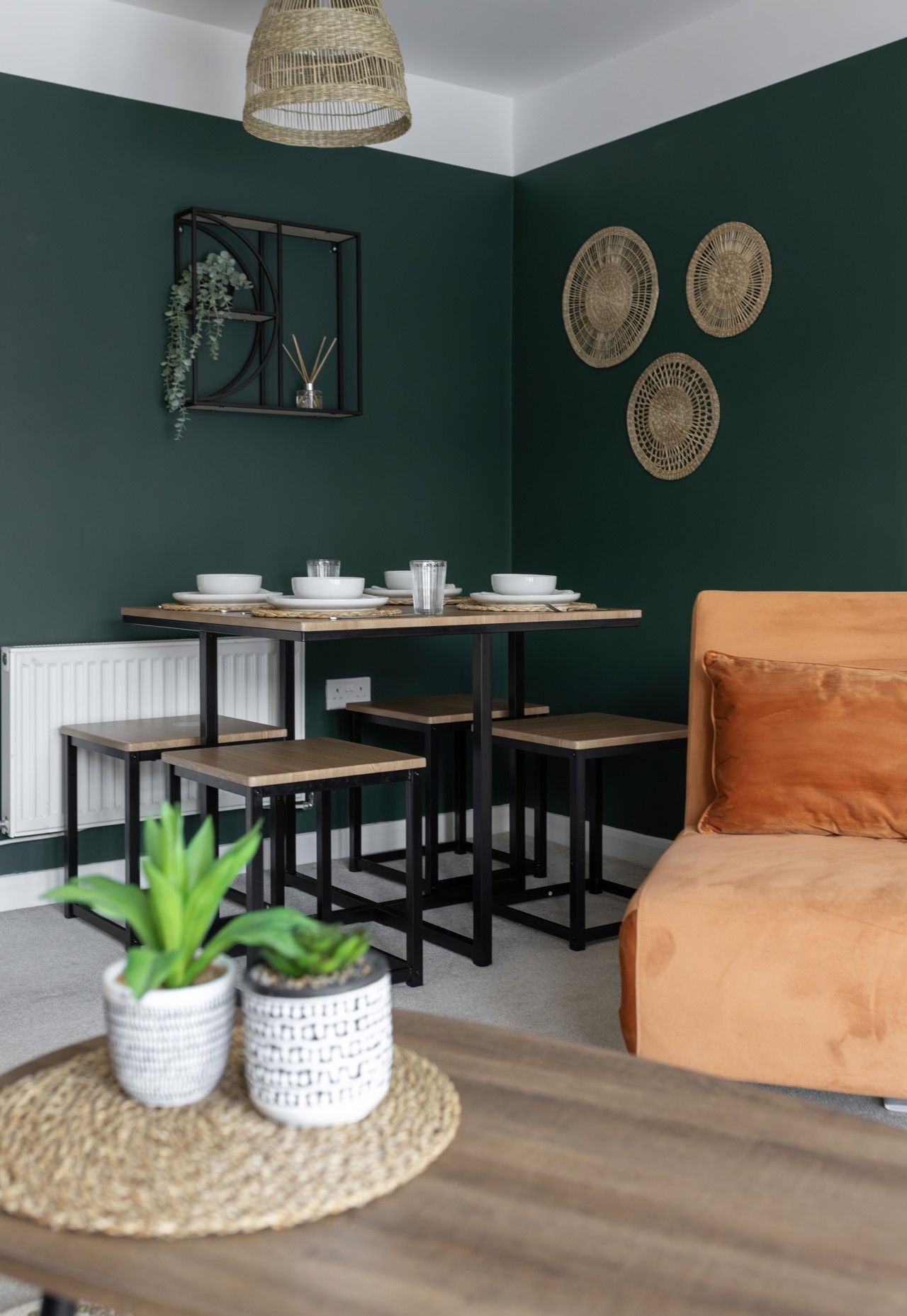 A dining area with a table set for four, a sofa, and decorative wall art.