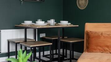 A dining area with a table set for four, a sofa, and decorative wall art.